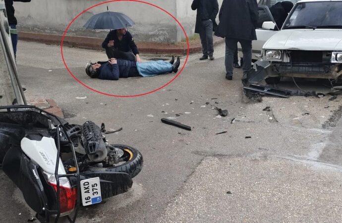 Motosiklet sürücüsünün yaralandığı bir kaza sonrasında, onun başında ıslanmaması için bir şemsiyeyle beklediği görüldü.